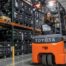 Operator driving a Toyota three-wheel electric forklift in a warehouse