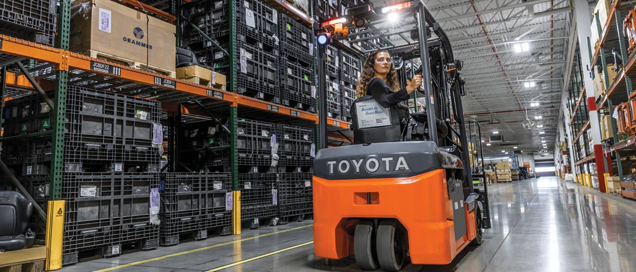 Operator driving a Toyota three-wheel electric forklift in a warehouse