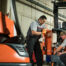 Two Toyota technicians beside a forklift with an open service panel
