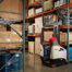 Operator using a Crown reach truck between warehouse pallet racks