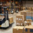 Crown reach truck moving a load through a warehouse staging area