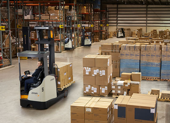 Crown reach truck moving a load through a warehouse staging area