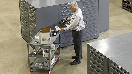 Person selecting a component beside labeled parts cabinets